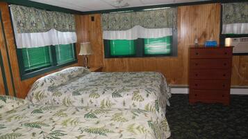 Quarto com cama, penteadeira e duas janelas com persianas verdes.