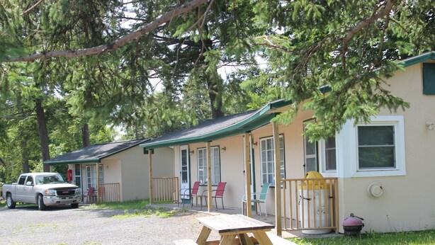 A cabin with a covered porch, picnic table, and a truck parked outside. - The Evergreen Motel (Oswego)