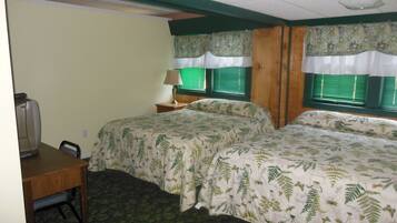 A hotel room with two beds, a desk, a chair, a lamp, and a television.