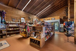 A rustic log cabin interior with wooden shelves displaying various souvenirs, a central display case, and a seating area. - Sun Outdoors Canyonlands Gateway (Moab)