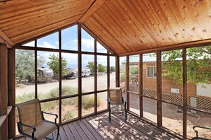 A covered porch with wooden flooring and large windows offering views of a parking area and outdoor scenery. - Sun Outdoors Canyonlands Gateway (Moab)