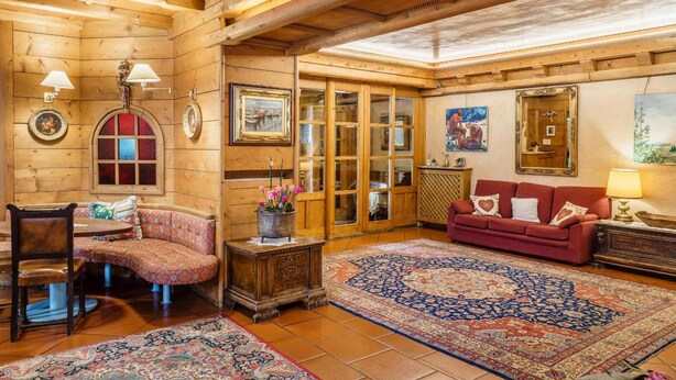 L'intérieur d'un chalet confortable, avec des murs en bois, un banc en bois, un canapé rouge et un tapis à motifs.