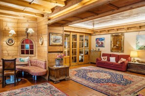 L'intérieur d'un chalet confortable, avec des murs en bois, un banc en bois, un canapé rouge et un tapis à motifs.
