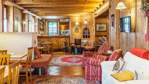 Un intérieur chaleureux en bois, avec un coin repas, un canapé et un bar.