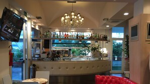 A bar area with a counter, chairs, and a red leather couch. - Hotel Miami (Ravenna)