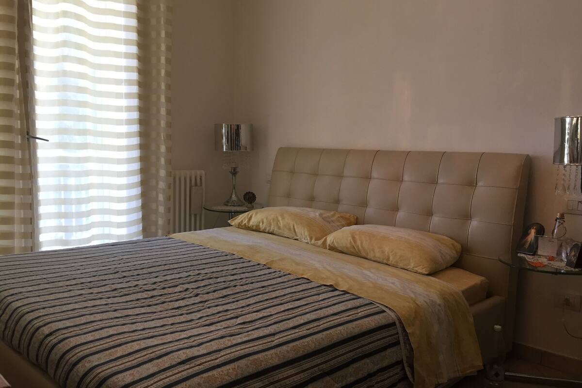 A bedroom with a bed, a bedside table, a lamp, and a radiator.