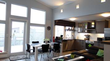 Una cocina moderna con comedor, ventanas amplias y un espacio de sala de estar acogedor con sofá.
