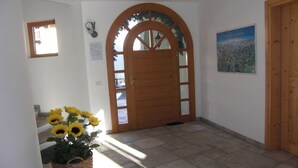 Ein Flur mit einer Holztür, einem gerahmten Bild an der Wand und einem Korb voller Sonnenblumen.