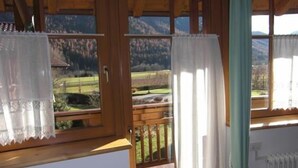 Eine Holzhütte mit großen Fenstern, Blick auf eine Berglandschaft und einer Holzterrasse.