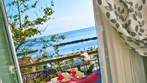 Un balcón con una mesa preparada para el té, un sofá y vistas al mar.