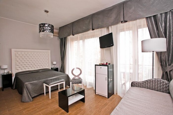 A modern hotel room with a large bed, a desk, a TV, and a wardrobe.