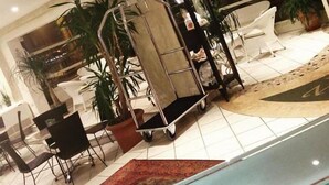 Un vestíbulo con mostrador de recepción, zona de estar y una planta grande en maceta.