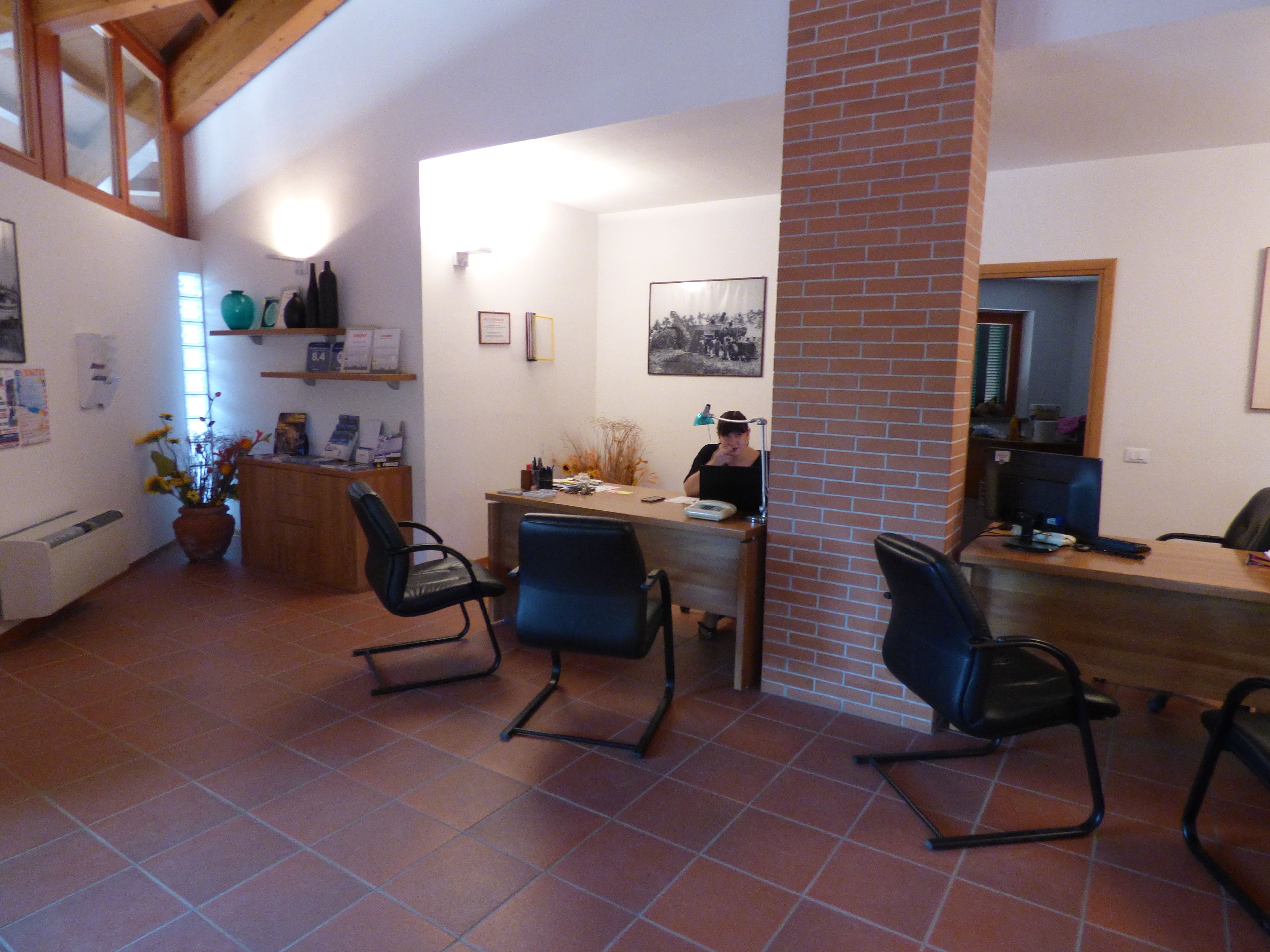 Una habitación amplia con techo alto, un pilar de ladrillo y una zona de escritorio con dos sillas.