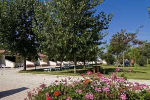 Un patio de hotel con mobiliario exterior, un parque infantil y un parterre de flores.