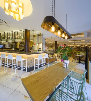 Eine moderne Bar mit einer Holztresen, weißen Barhocker und hängenden Lampen.
