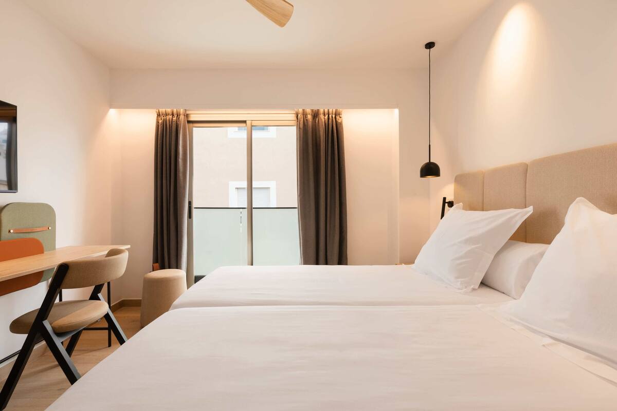 Ein Hotelzimmer mit Bett, Schreibtisch und Stuhl.