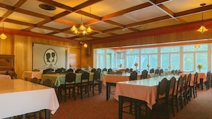 A banquet hall with tables set for dining, a large window with a view, and a wooden ceiling with exposed beams. - Stiles Motel Hill View Woodstock NB (Woodstock)