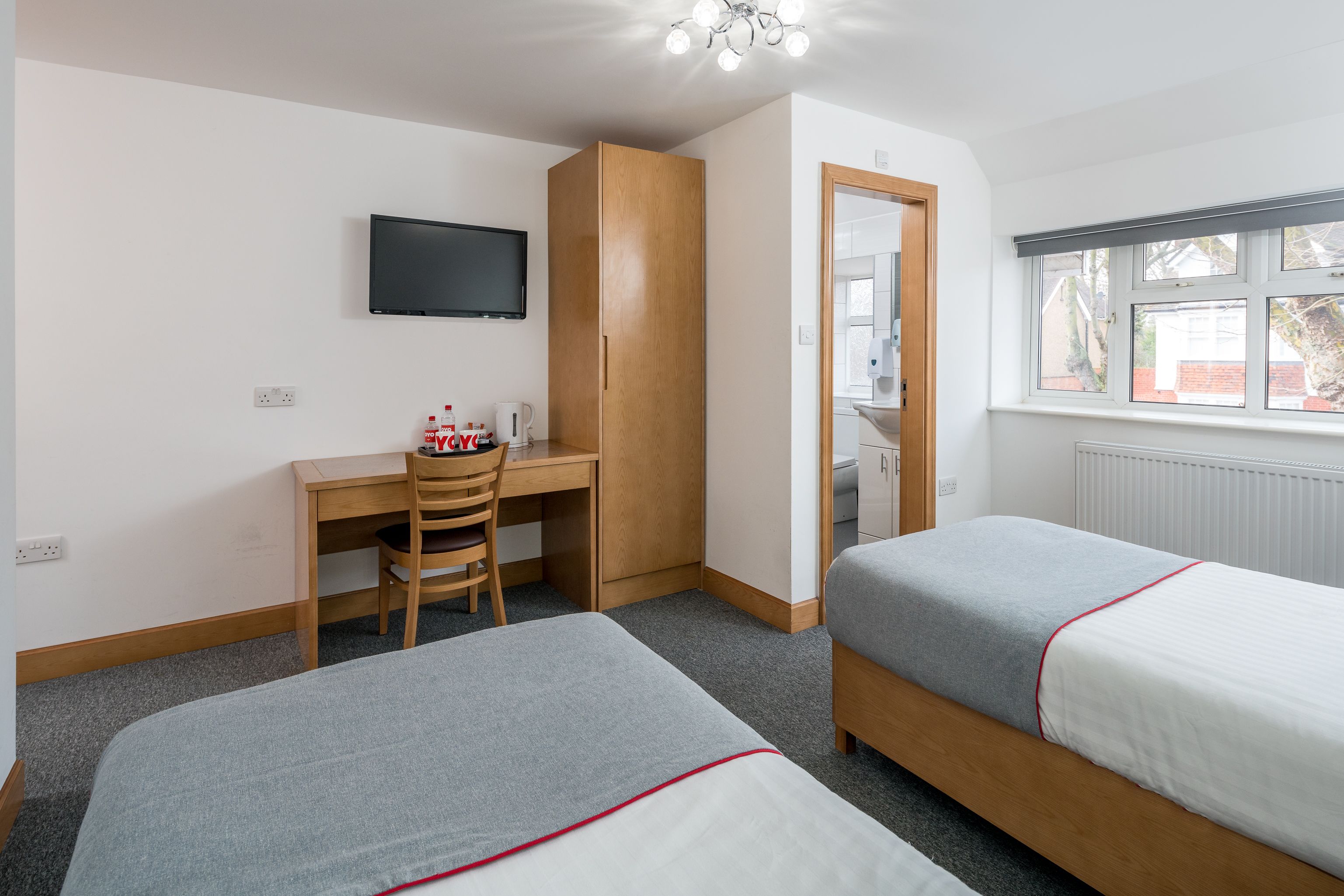 Habitación de hotel con dos camas, un escritorio, una silla, un televisor y una ventana.