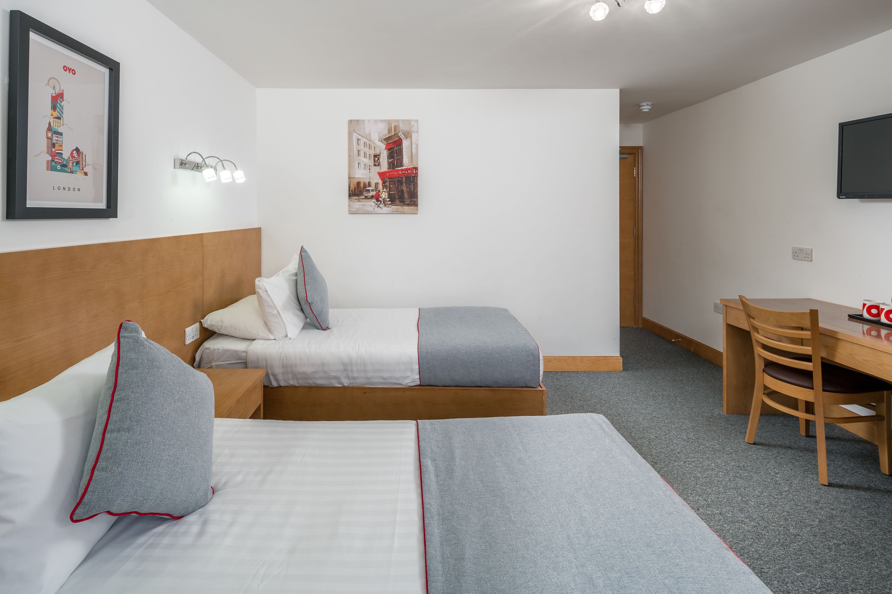 Ett hotellrum med två sängar, ett skrivbord, en stol och en tv på väggen.