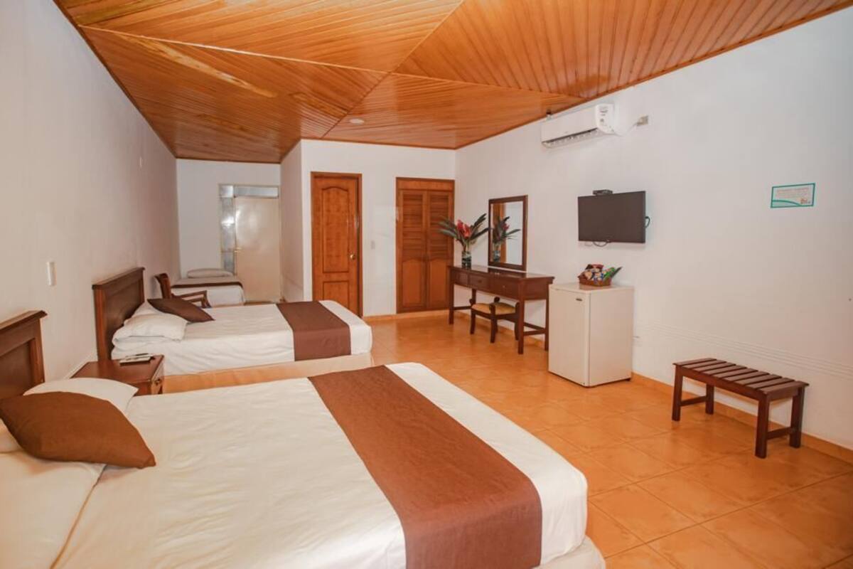 Une chambre d’hôtel avec deux lits, un bureau, une chaise, une télévision et une petite table.