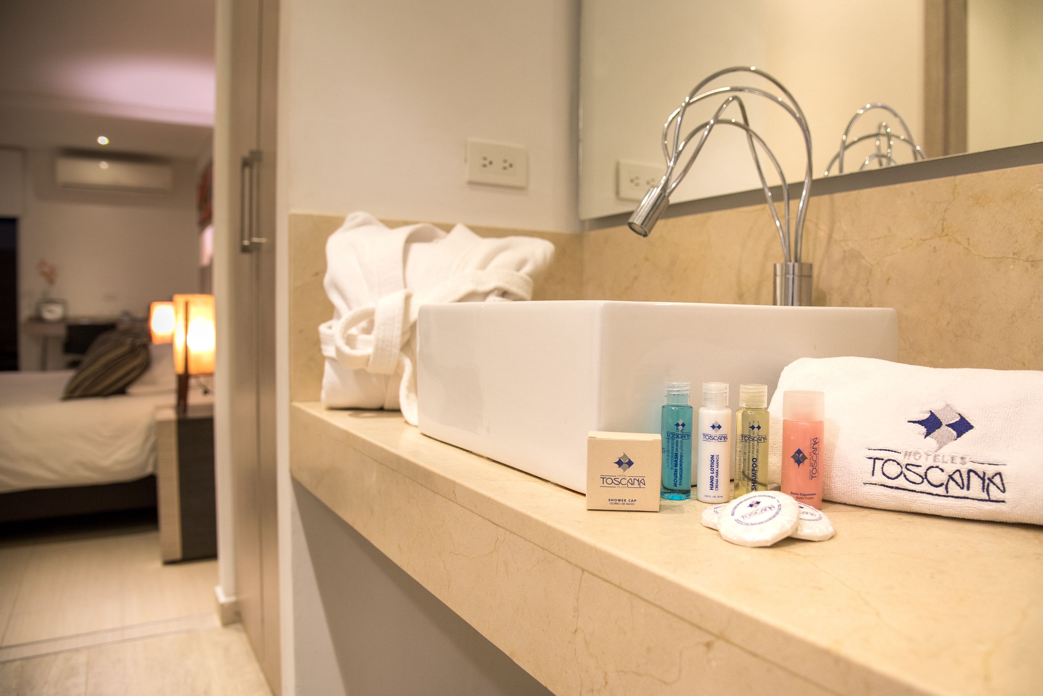 A hotel bathroom with a sink, toiletries, and a towel rack.