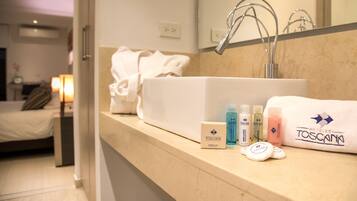 A hotel bathroom with a sink, toiletries, and a towel rack.