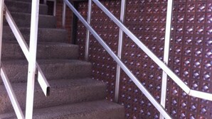 Una escalera con barandas metálicas y un revestimiento de pared decorativo.