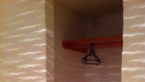 Un baño con paredes blancas con textura, un toallero rojo y suelo de baldosas.