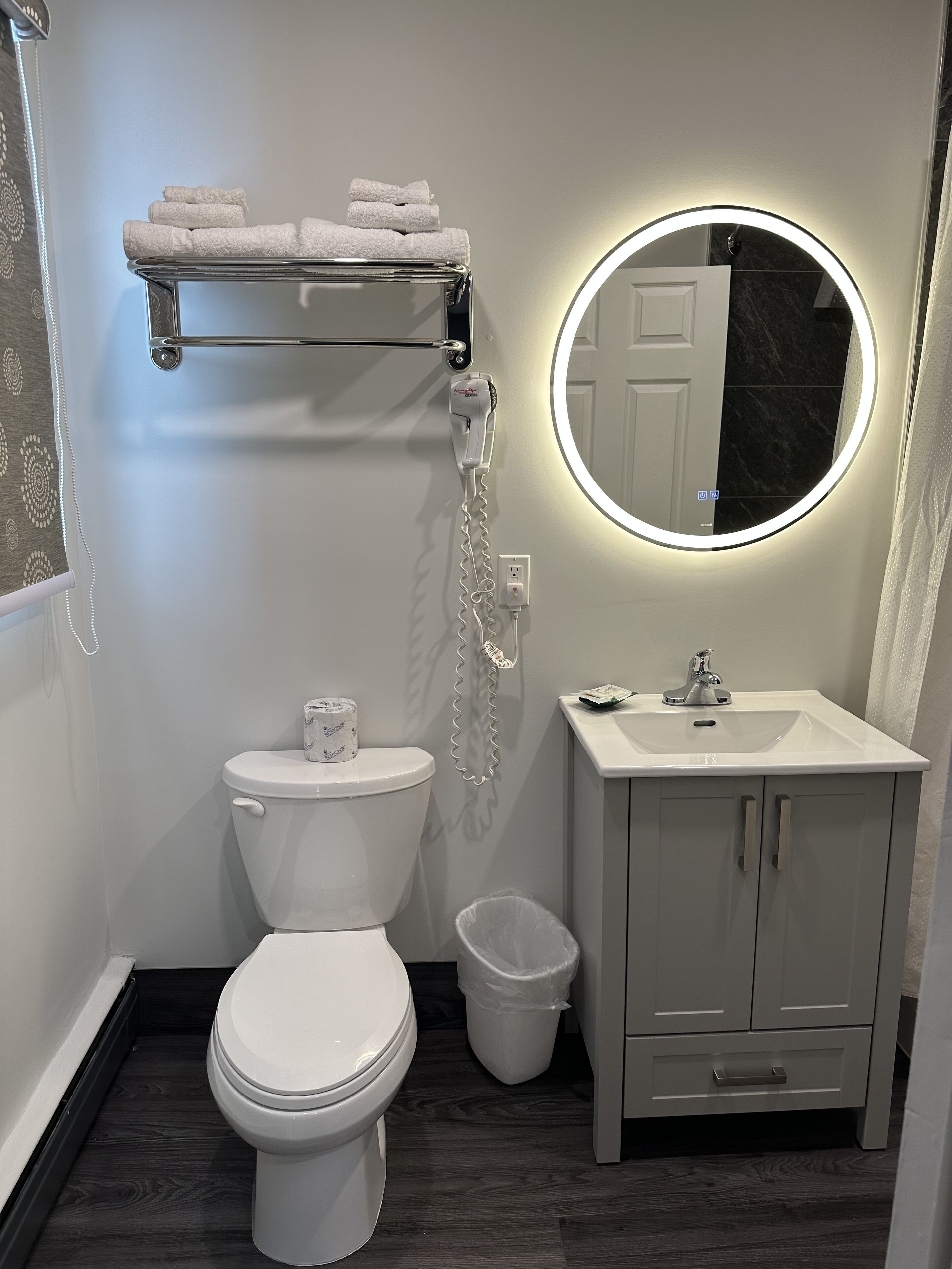 A bathroom with a toilet, a sink, a mirror, and a towel rack.