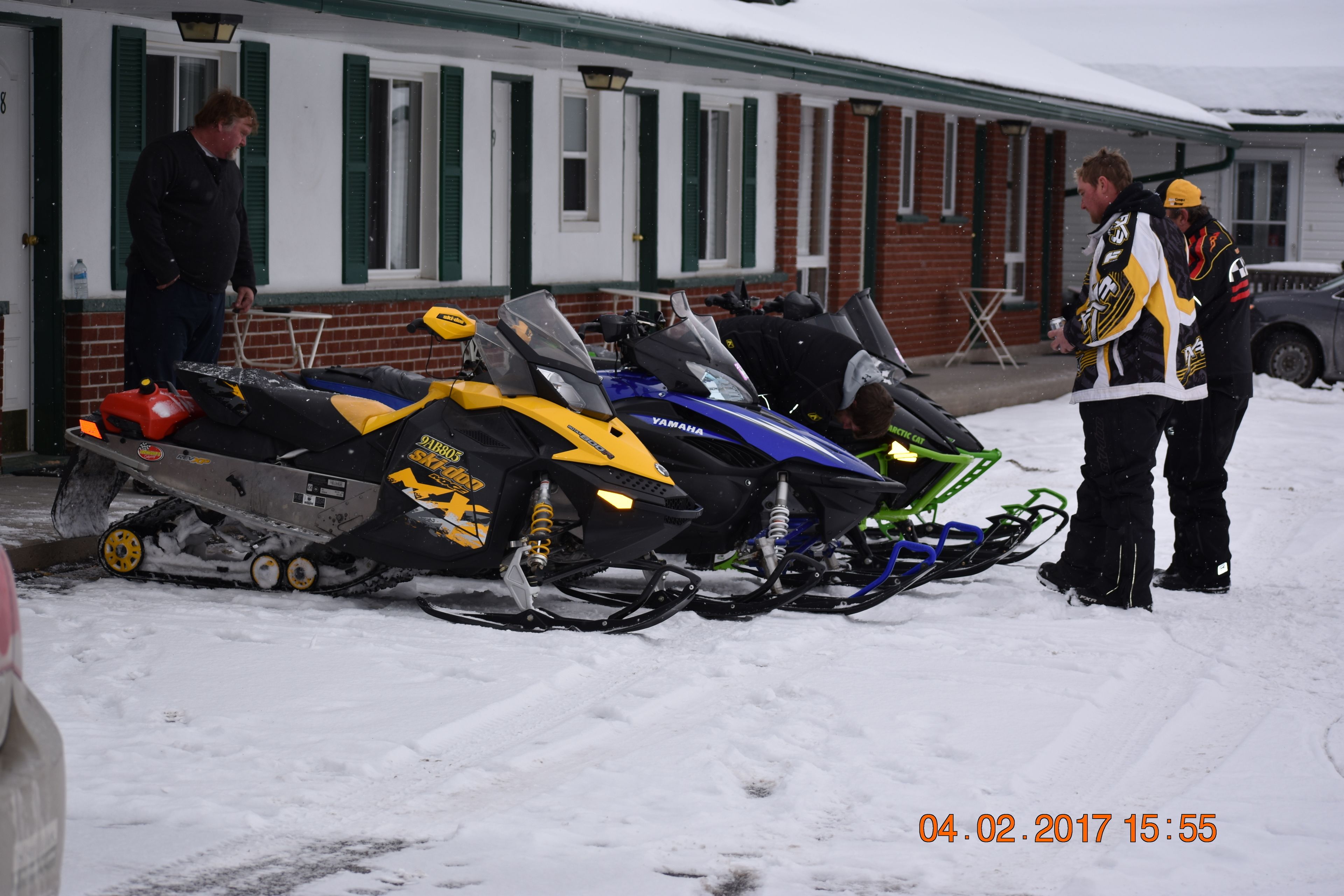 Una moto de nieve estacionada frente a un edificio con fachada de ladrillo y persianas verdes.
