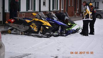 A snowmobile parked in front of a building with a brick facade and green shutters.