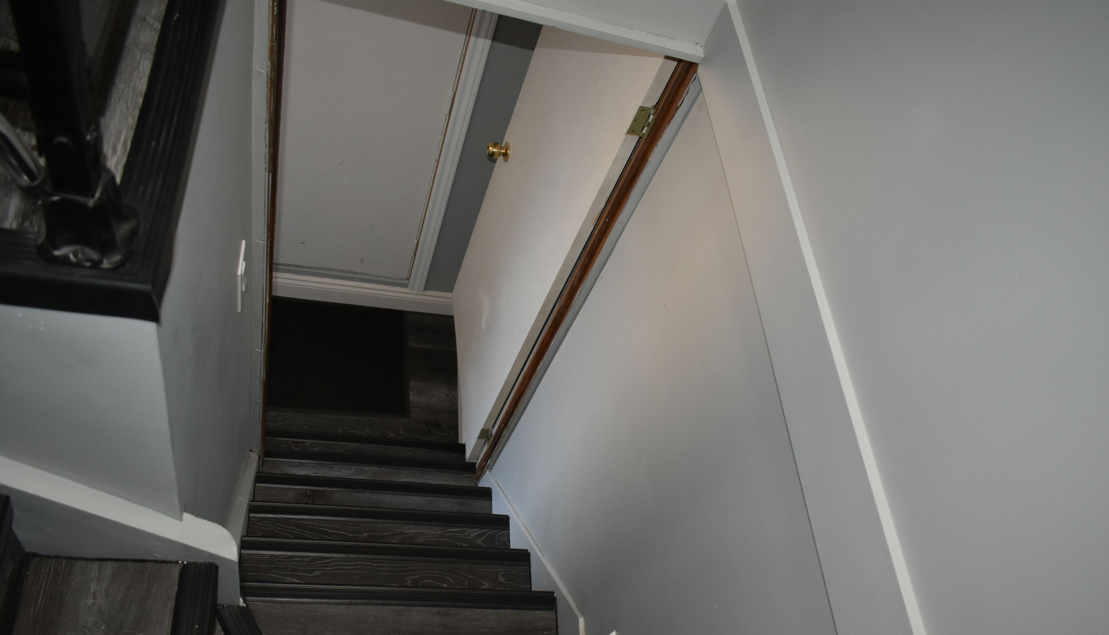 A staircase with dark wooden steps leading to a door with a brass handle.