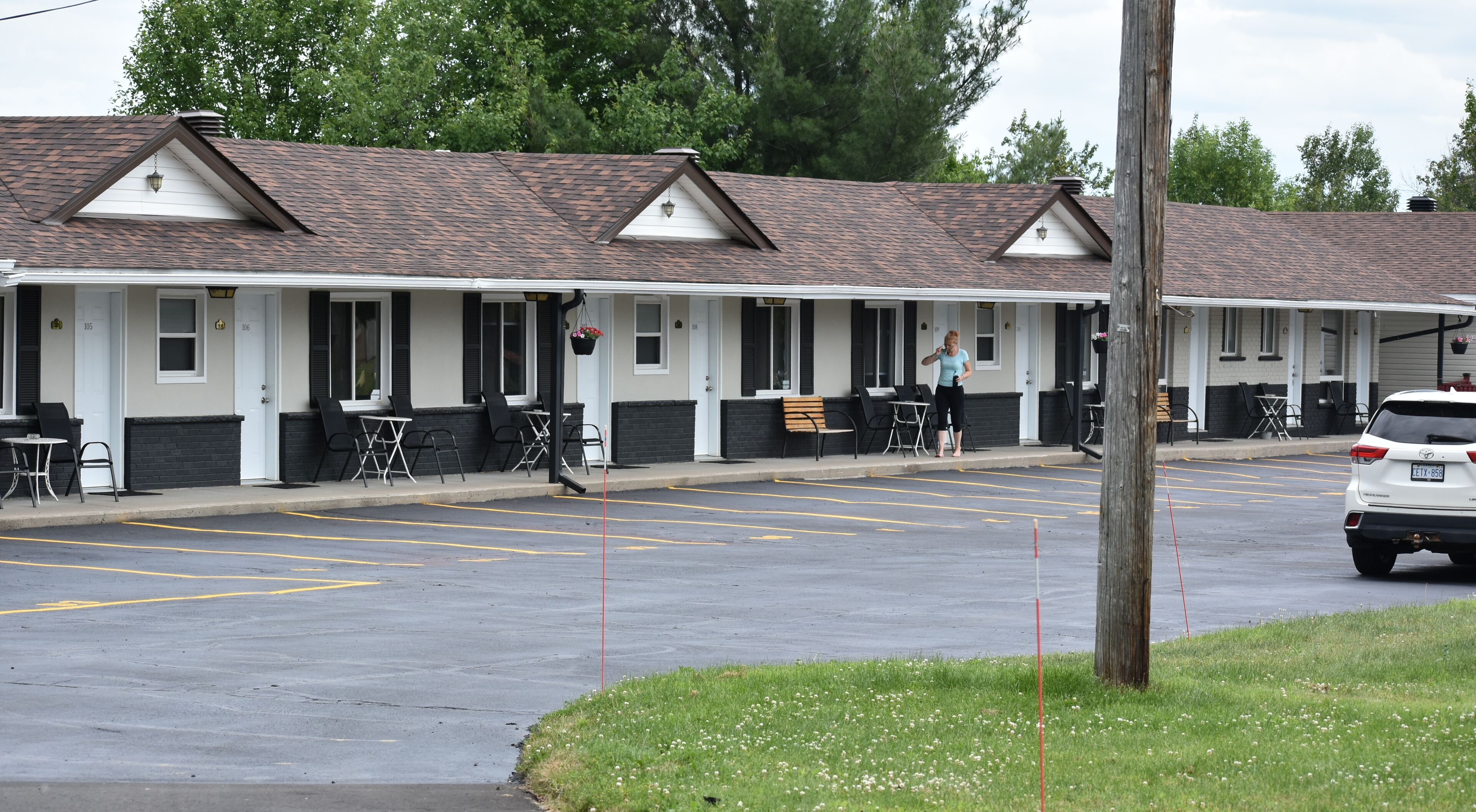 A motel with a row of rooms, outdoor seating, and a parking lot.