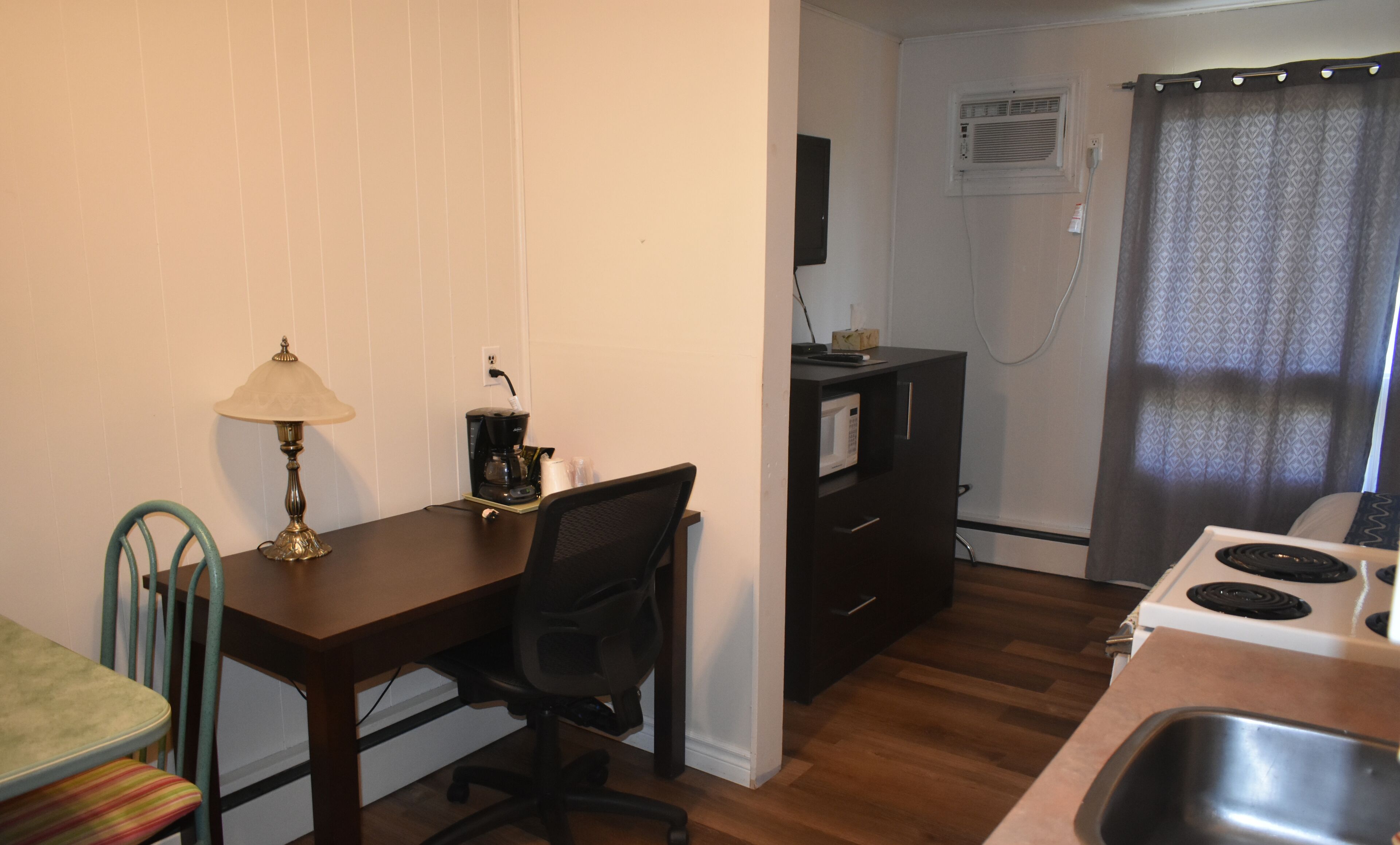 A compact kitchen with a dining table, chairs, a coffee maker, a microwave, and a stove.