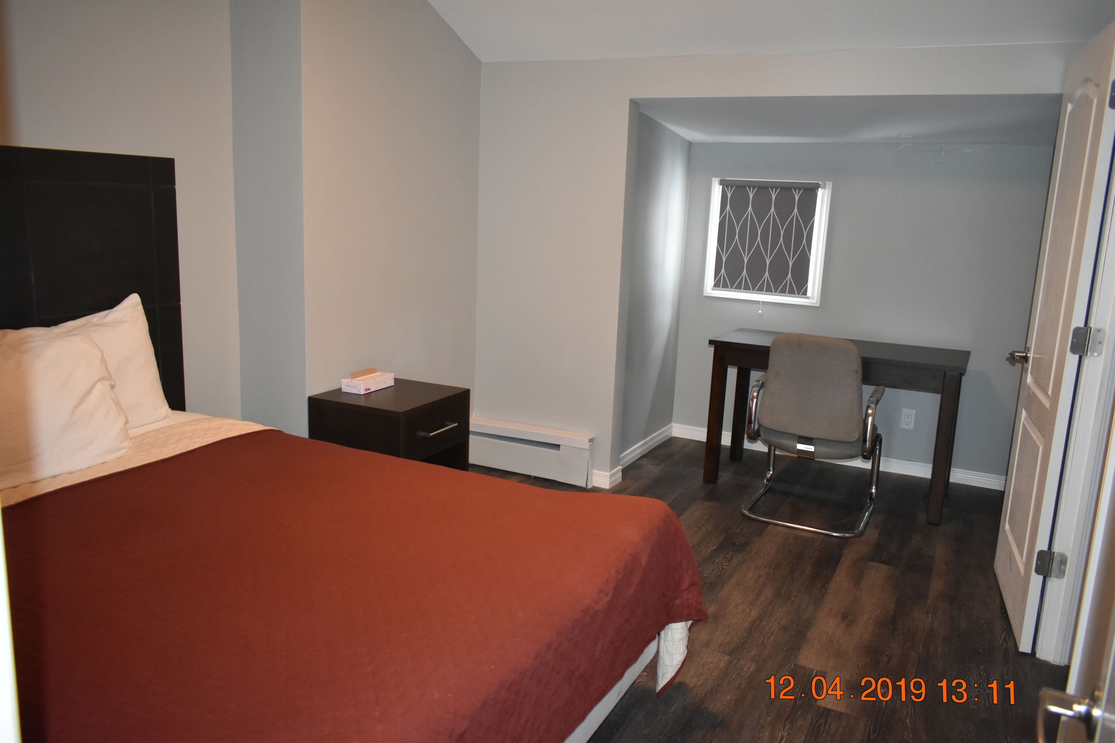 A hotel room with a bed, a desk, and a chair.