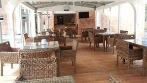 An indoor dining area with wicker furniture and a brick wall. - Hotel Toscana Oriente (El Carmen de Viboral)