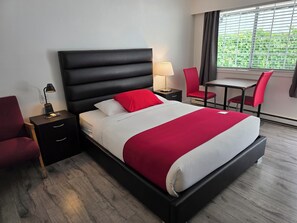 A hotel room with a bed, bedside tables, a desk, and chairs.