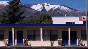 A building with a blue and white facade, a parking lot, and a mountain with snow in the background. - The Monticello Inn (Monticello)