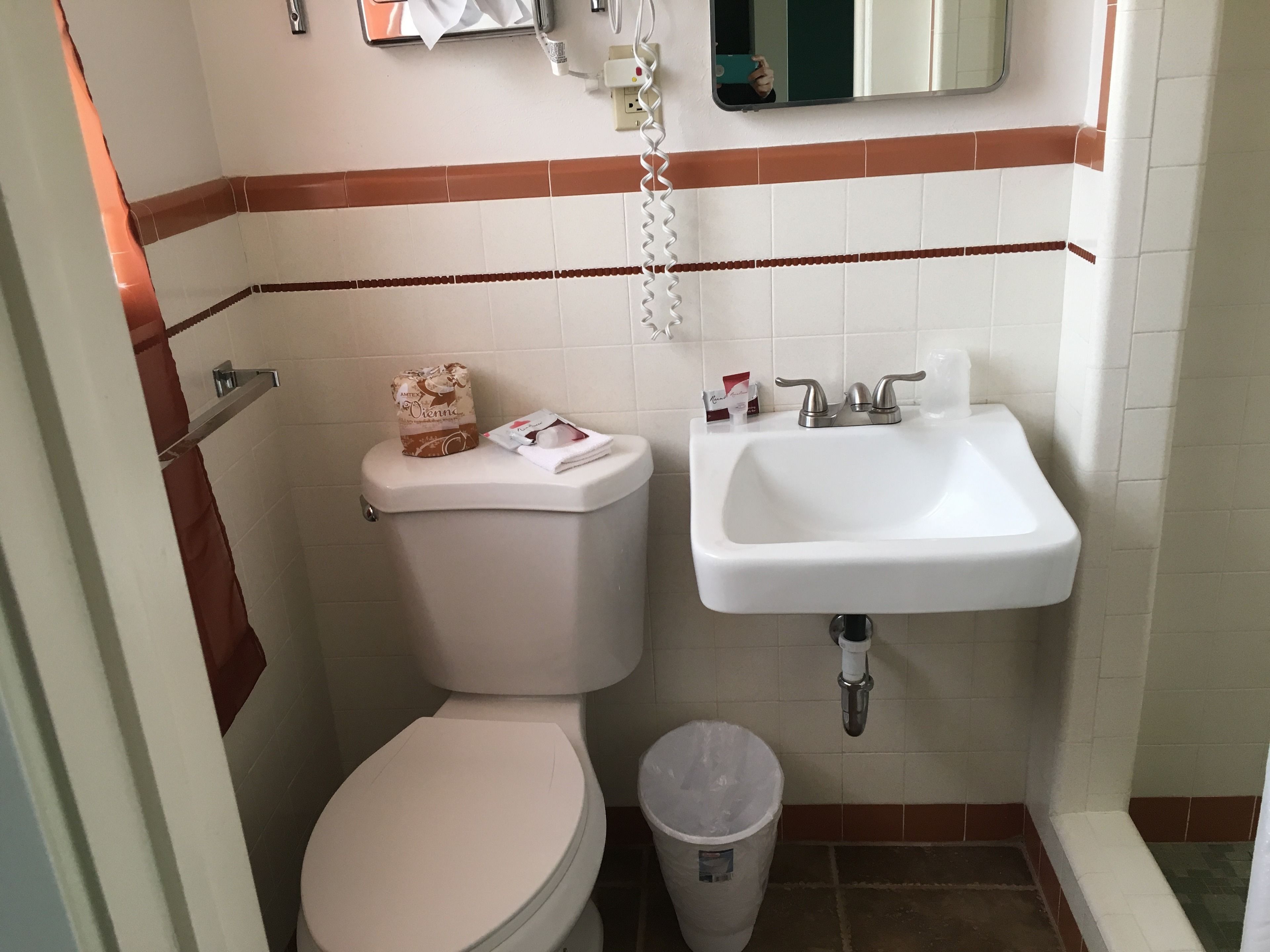 A bathroom with a toilet, sink, and trash can.