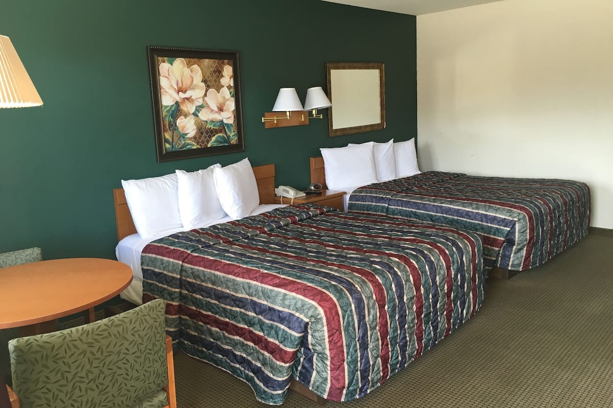Hotellihuone, jossa on kaksi sänkyä, pieni pöytä ja tuoli.
