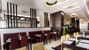 A modern restaurant with dark wooden tables and red booths, featuring a clean, minimalist design and a sign that reads "Hotel Best Night". - Best Night (Algiers)