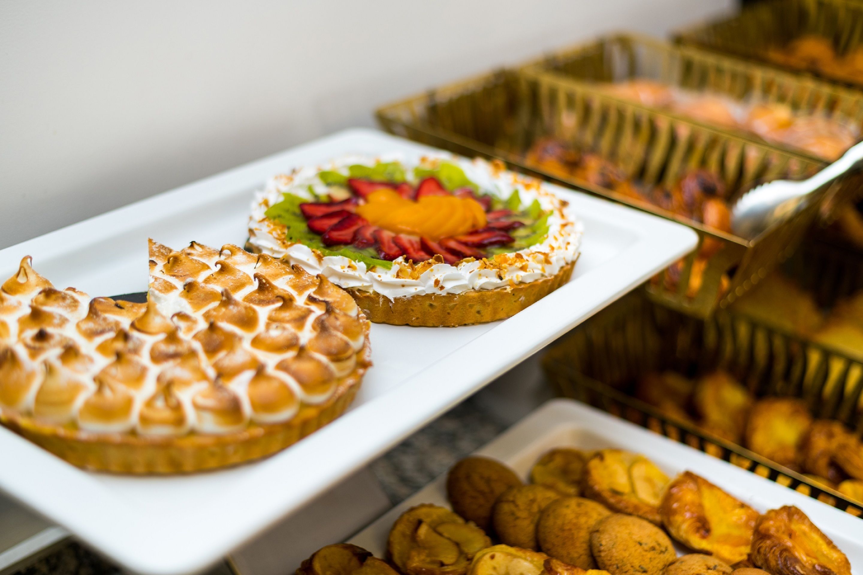 Un buffet proposant une variété de desserts, notamment un gâteau surmonté de meringue et une tarte garnie de fruits.