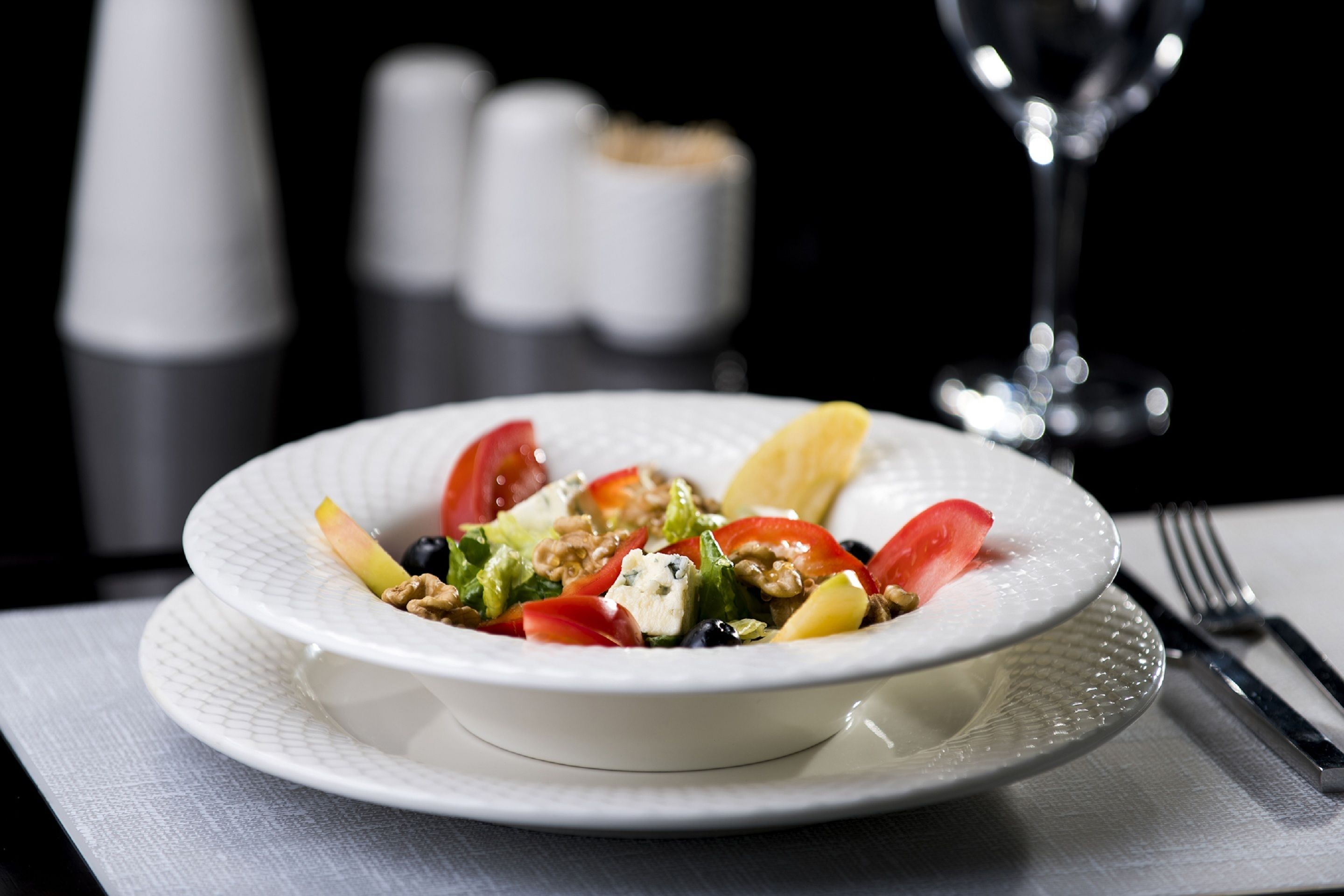 Une assiette blanche avec une salade, posée sur une serviette blanche.