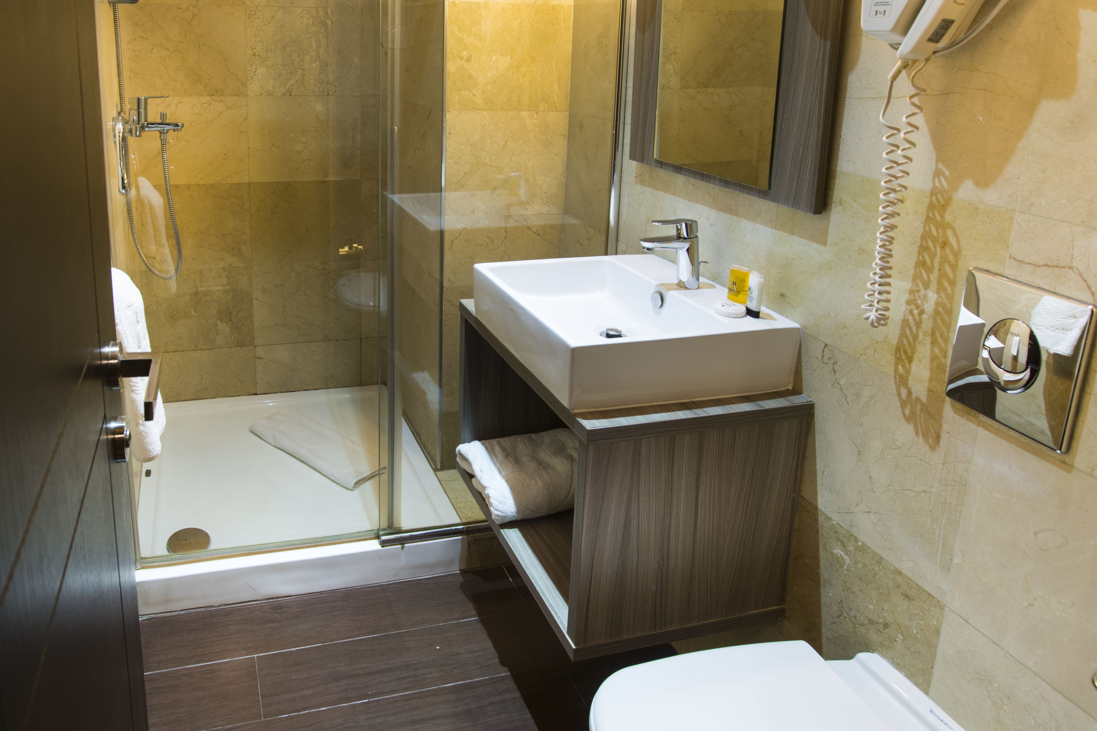 A modern bathroom with a glass-enclosed shower, a white sink, and a wooden vanity.