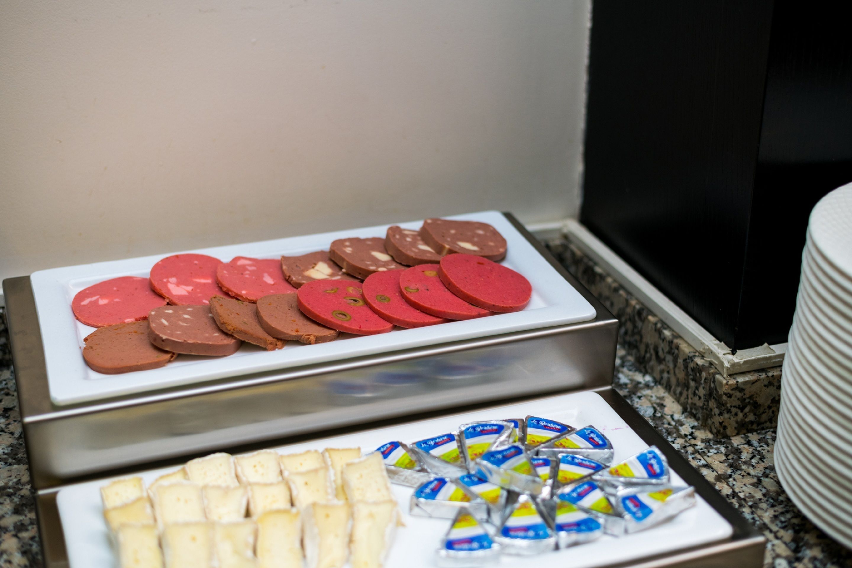 A buffet with various food items including sliced meats and packaged snacks.
