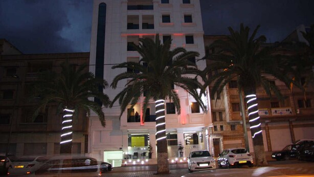 A hotel named Hotel Best Night with a modern facade, palm trees in front, and a well-lit entrance. - Best Night (Algiers)