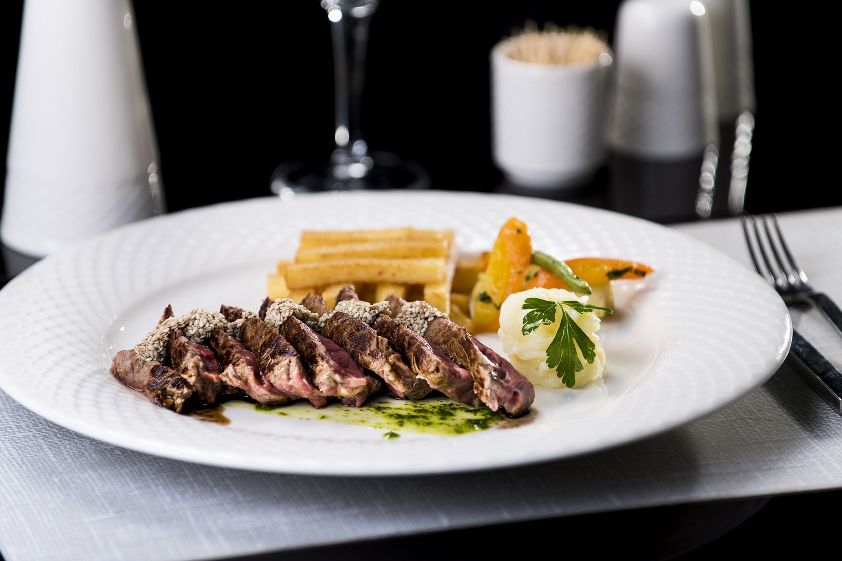 Une assiette de steak frites, accompagnée d’une portion de légumes, le tout servi dans une assiette blanche.