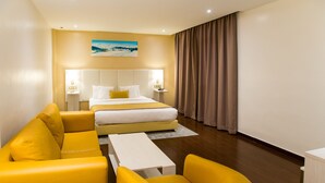 A hotel room with a bed, a yellow sofa, a small table, and a large window with curtains. - Best Night (Algiers)