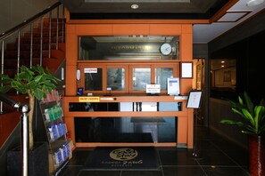 A reception desk with a clock, a directory, and a sign for 'Good Stay'.
