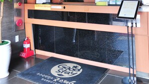 A reception desk with a clock, informational posters, and a fire extinguisher. - Goodstay Daegwallyeongsanbang (Pyeongchang)